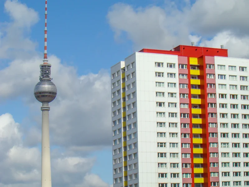 Cédric · 17/05/2012 · 2048 x 1536 Cette photographie met en scène la **Tour de la Télévision de Berlin** (Fernsehturm) en arrière-plan, symbole emblématique. À droite, un immeuble résidentiel aux couleurs vives (jaune, rouge et noir) domine.La **composition** oppose l'élégance futuriste de la tour à l'architecture fonctionnelle et colorée du bâtiment. Le **cadrage** est serré, capturant une partie du ciel bleu et quelques nuages.La **lumière** est naturelle, avec un éclairage doux, mettant en valeur les teintes vives. Les **couleurs dominantes** sont les tons chauds (rouge, jaune) et le gris métallique de la tour. L’ambiance est **urbaine et dynamique**, mêlant modernité et vie quotidienne.