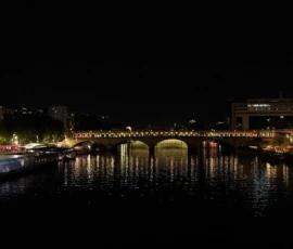 Dominique · 24/05/2026 · 1700 x 1133 Cette photographie met en scène un **pont éclairé** enjambant un fleuve la nuit. Le **sujet principal** est le pont, dont les arches et les lumières créent un jeu graphique.La **composition** est équilibrée, avec une perspective axiale le long de l’eau. Le **cadrage** est large, capturant aussi les reflets et les bâtiments environnants.Les **lumières** dominent, avec des teintes **jaunes et blanches**, contrastant avec le noir de la nuit. Les **couleurs** sont sobres, avec des touches bleutées dans l’eau.Le style est **réaliste et nocturne**, évoquant une **ambiance calme et mystérieuse**, presque onirique.