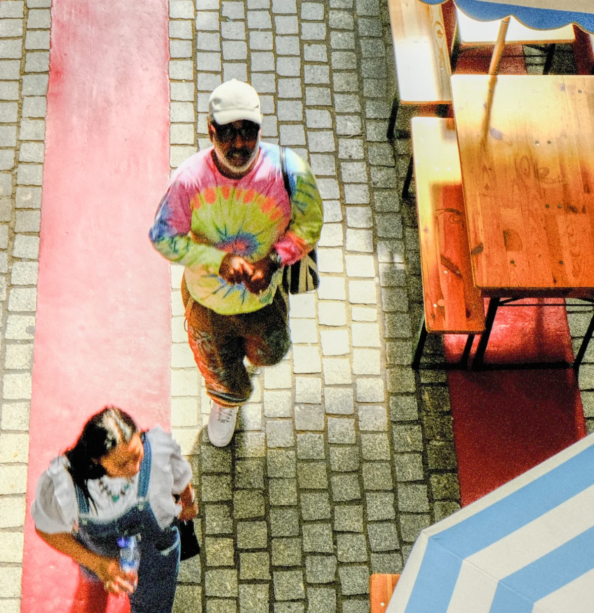 Nathalie F. · 25/04/2026 · 3606 x 3725 Cette photographie capture deux skateurs en mouvement sur une rampe. Le sujet principal est le skateur en haut, vêtu d’un t-shirt tie-dye coloré et d’un bonnet blanc, contrastant avec celui en bas, plus discret.La composition est dynamique, avec un cadrage en plongée accentuant le mouvement. Les couleurs dominantes sont vives (rose, bleu, vert) et contrastées, créant une ambiance énergique et urbaine. La lumière semble naturelle, bien que légèrement surexposée, renforçant l’aspect vibrant de la scène. Le style est spontané et street, évoquant une ambiance jeune et décontractée.