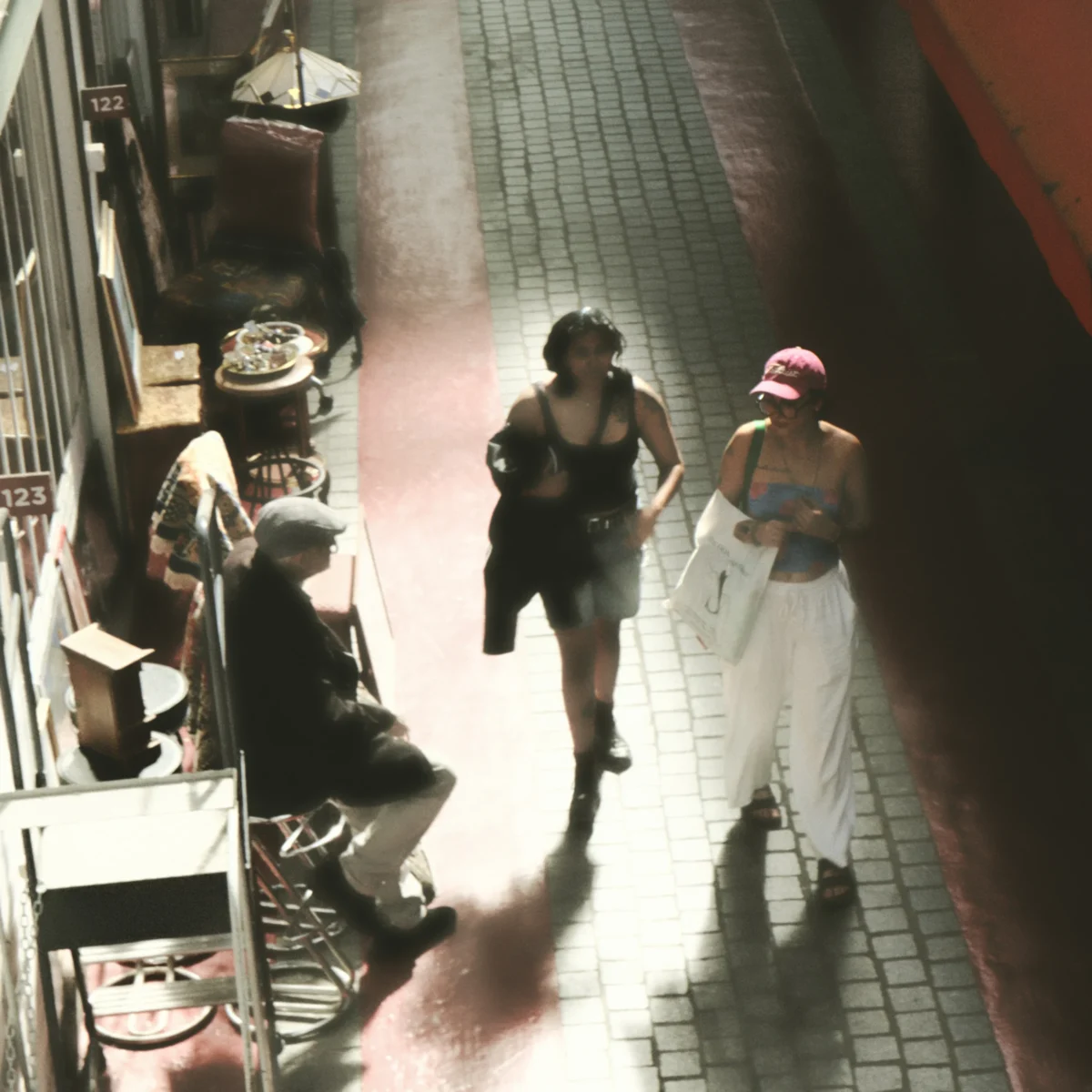 Nathalie F. · 25/04/2026 · 4160 x 4160 Cette photographie semble être une image de surveillance floue. Le **sujet principal** est un groupe de trois personnes marchant côte à côte, dont une porte un vêtement clair et un chapeau.La **composition** est dynamique, avec un cadrage serré sur les individus en mouvement. La **lumière** est tamisée, créant des ombres marquées et une ambiance peu distincte. Les **couleurs dominantes** sont des tons neutres et grisâtres, avec des reflets rouges et blancs.Le **style** est documentaire et technique, typique des images de vidéosurveillance. L’**ambiance** est anonyme et légèrement mystérieuse, renforcée par la faible netteté.