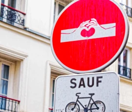 Monique · 20/05/2026 · 3946 x 4161 Cette photographie montre deux panneaux routiers. Le sujet principal est un panneau circulaire rouge avec une main tenant un objet, surmontant un panneau rectangulaire blanc indiquant "SAUF" avec un symbole de vélo.La composition est verticale, avec un cadrage serré sur les panneaux. L’arrière-plan montre une façade d’immeuble parisien typique. La lumière est naturelle, douce et légèrement diffuse, créant des ombres peu marquées. Les couleurs dominantes sont le rouge vif du panneau supérieur et les tons neutres de la façade. Le style est documentaire et urbain, évoquant une ambiance de ville dynamique et réglementée.