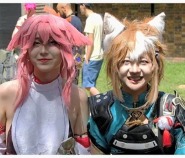 Sophie · 1897 x 1263 Cette photographie montre deux personnes déguisées en cosplay. Le sujet principal est leur tenue colorée et stylisée, évoquant des personnages de jeux vidéo ou d’anime.La composition est centrée sur eux, avec un cadrage serré. L’arrière-plan flou révèle un environnement extérieur, probablement une convention. La lumière est naturelle et douce, mettant en valeur les couleurs vives.Les couleurs dominantes sont le rose vif, le bleu électrique, et le blanc, créant un contraste dynamique. Le style est festif et ludique, avec une ambiance joyeuse et décontractée, typique des événements geek.