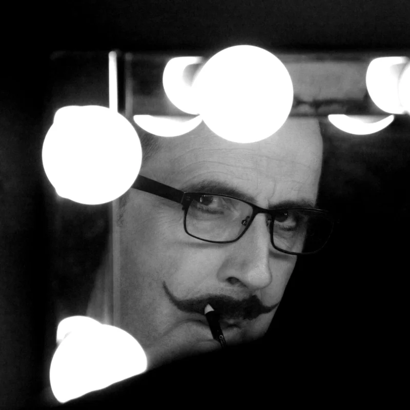 Dominique · 15/12/2013 · 2592 x 2592 Cette photographie met en scène un homme comme sujet principal, vu de face avec un cadrage serré. Il porte des lunettes et une moustache, adoptant une expression sérieuse.La composition est centrée sur son visage, partiellement masqué par des formes circulaires lumineuses en arrière-plan. Le cadrage est serré, créant une intimité.La lumière est contrastée, avec des taches lumineuses blanches qui ajoutent un effet dramatique. Les couleurs dominantes sont les tons de gris, typiques d'une photo en noir et blanc.Le style est sobre et artistique, évoquant une ambiance mystérieuse et introspective.