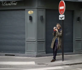 Elisa Ma · 16/05/2026 · 5596 x 3910 Cette photographie met en scène une personne comme sujet principal, prise en train de photographier un bâtiment. La composition est simple et épurée, avec un cadrage serré sur le sujet et l’arrière-plan minimaliste.La lumière semble naturelle, probablement en journée, mais un peu tamisée, créant des ombres douces. Les couleurs dominantes sont les tons gris (bâtiment, vêtements) et marron, avec une touche de rouge vif (panneau d’interdiction).Le style est réaliste et documentaire, évoquant une ambiance urbaine et calme, presque intimiste.