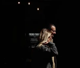 Elisa Ma · 16/05/2026 · 1176 x 2648 Cette photographie capture deux personnes marchant de dos devant une façade sombre. Le sujet principal semble être l’ambiance nocturne et urbaine.La composition est simple, avec un cadrage serré sur les silhouettes. La lumière est faible et contrastée, créant des ombres marquées. Les couleurs dominantes sont les teintes sombres (noir, gris) avec des touches de bleu et blanc.Le style est réaliste et spontané, évoquant une ambiance mystérieuse et moderne. L’éclairage artificiel et les néons ajoutent une touche contemporaine et légèrement mélancolique.