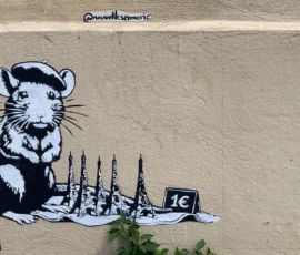 Kerry · 09/05/2026 · 3447 x 2230 Cette photographie montre un graffiti mural représentant une souris tenant une maquette de gratte-ciel avec la lettre "C" stylisée. Le sujet principal est ce rat stylisé, symbole souvent associé à Banksy.La composition est épurée, avec un cadrage serré sur le graffiti. La lumière naturelle éclaire uniformément la scène, mettant en valeur les contours nets et les contrastes. Les couleurs dominantes sont le noir, le blanc et le bleu, créant un style graphique et minimaliste. L’ambiance est à la fois humoristique et critique, typique de l’art urbain.
