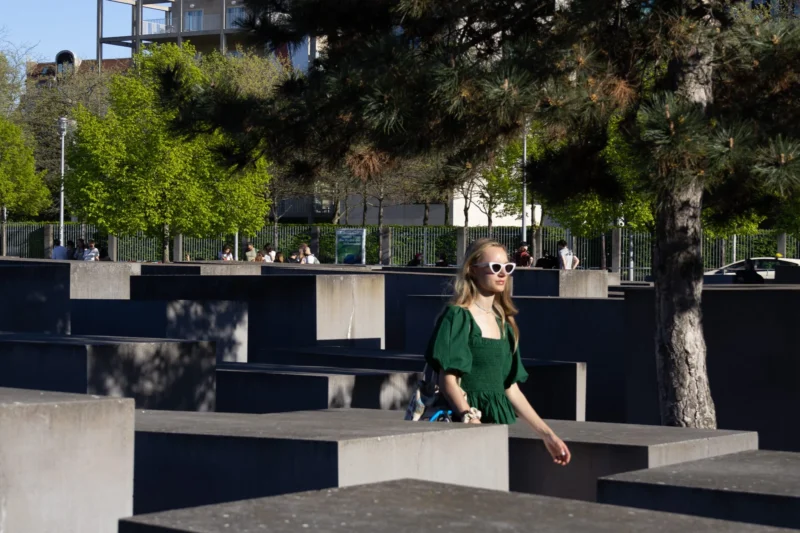 Muriel · 01/05/2026 · 2048 x 1365 Cette photographie met en scène une femme en vert comme sujet principal, assise sur des structures géométriques en béton. La composition joue sur les lignes droites et les contrastes entre les formes urbaines et la nature environnante.Le cadrage est serré sur elle, avec un arrière-plan flou mais identifiable, incluant des arbres et des bâtiments. La lumière est naturelle et semble provenir d’un angle latéral, créant des ombres marquées. Les couleurs dominantes sont les tons verts de sa tenue et les gris des structures en béton.L’ambiance est à la fois moderne et apaisante, mêlant urbanité et sérénité naturelle.