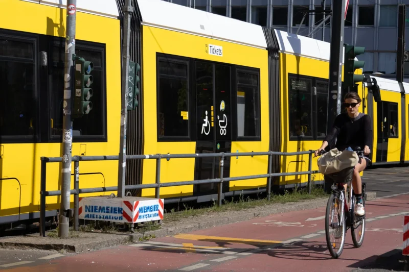 Muriel · 03/05/2026 · 2048 x 1365 Cette photographie met en scène un cycliste en premier plan, vêtu d’une tenue sombre, roulant près d’un tramway jaune vif. Le sujet principal est ce contraste entre le cycliste et le tram, soulignant le thème des transports urbains.La composition est dynamique, avec un cadrage serré sur le cycliste et le tram en arrière-plan. La lumière semble naturelle, bien que légèrement tamisée, créant des ombres douces. Les couleurs dominantes sont le jaune éclatant du tram et les tons neutres du cycliste et de l’environnement urbain.L’ambiance est moderne et quotidienne, reflétant une ville active et bien organisée.
