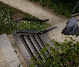Muriel · 09/05/2026 · 2048 x 1365 Cette photographie met en scène un **fauteuil de jardin noir** renversé et une **pelle** posée à côté, sur un sol en béton et des plantes. Le **sujet principal** est ce mobilier abandonné, évoquant un abandon ou une négligence.La **composition** est simple et épurée, avec un **cadrage serré** centré sur ces éléments. La **lumière** semble naturelle, douce, mais un peu tamisée, créant des ombres légères. Les **couleurs dominantes** sont les tons verts des plantes, le noir du fauteuil et le gris du sol.Le **style** est réaliste et documentaire, tandis que l’**ambiance** est mélancolique, presque déserte.