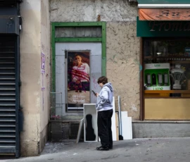 Muriel · 16/05/2026 · 2048 x 1365 Cette photographie montre une femme en uniforme, probablement une policière, marchant devant un bâtiment urbain. Le sujet principal est cette femme, cadrée en plan moyen.La composition inclut une enseigne de magasin à droite et une affiche publicitaire à gauche. La lumière est naturelle, légèrement tamisée, créant des contrastes doux. Les couleurs dominantes sont les tons neutres (gris, beige) avec des touches de vert et de bleu.Le style est réaliste et documentaire, capturant une scène quotidienne. L’ambiance est sobre et urbaine, évoquant une atmosphère calme et professionnelle.