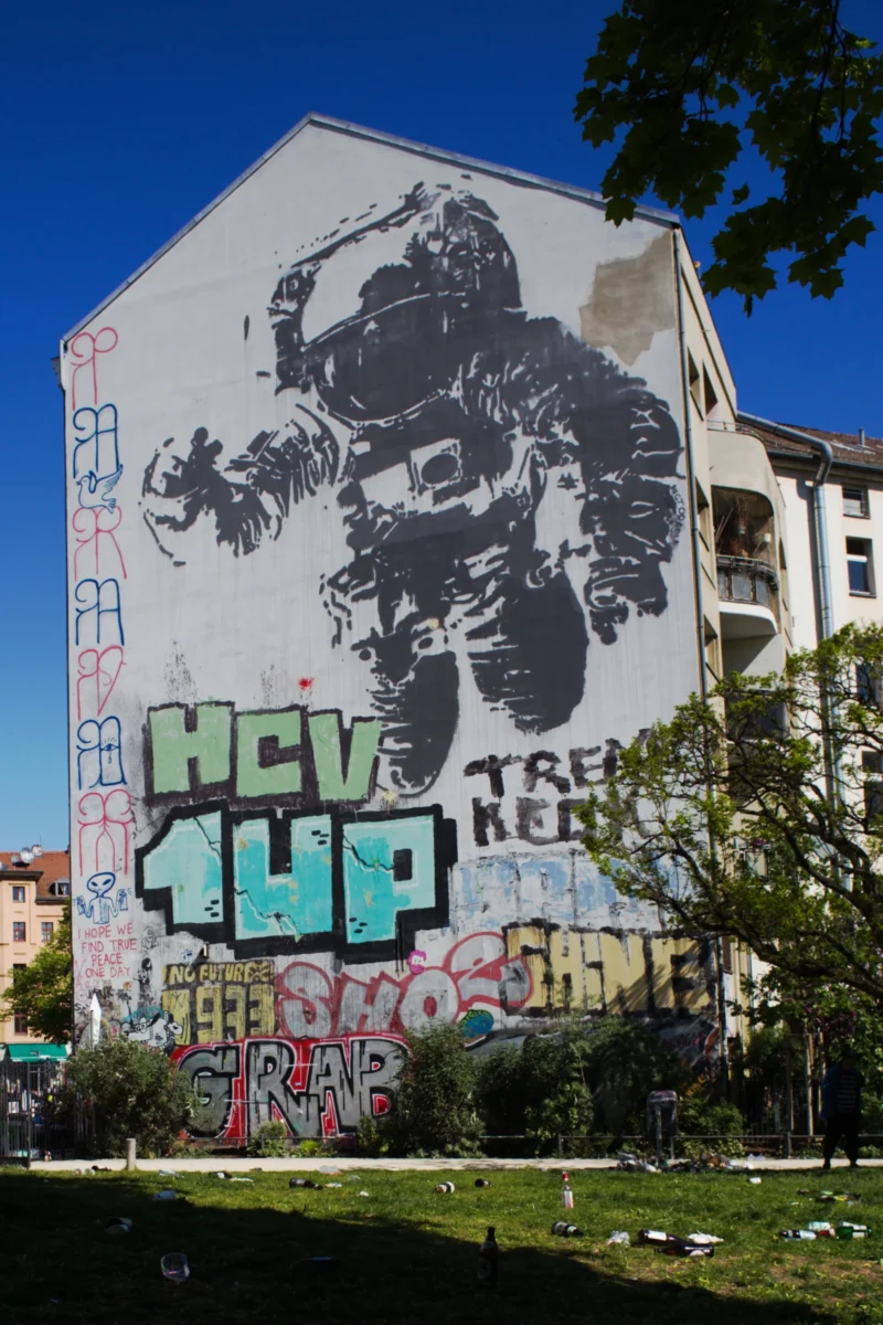 Fabienne · 02/05/2026 · 2520 x 3780 Cette photographie montre un bâtiment tagué avec un graffiti imposant. Le sujet principal est une grande illustration monochrome d’un gorille stylisé, entourée de tags colorés comme "HCV 1UP".La composition met en valeur le mur central, avec un cadrage serré qui isole le graffiti. La lumière naturelle éclaire uniformément la scène, accentuant les contrastes. Les couleurs dominantes sont le noir et blanc pour le gorille, et des teintes vives (bleu, vert, rouge) pour les inscriptions.Le style est urbain et artistique, reflétant une ambiance dynamique et rebelle, typique de la culture street art.