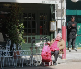 Sophie · 4039 x 2848 Cette photographie capture une scène urbaine paisible. Le sujet principal est une femme assise sur un banc, vêtue d’une veste rose, avec un enfant à côté d’elle. En arrière-plan, un homme en combinaison de travail est visible près d’une porte verte.La composition joue sur les contrastes entre intérieur et extérieur, avec des éléments architecturaux et des détails urbains. Le cadrage est serré, mettant en valeur les personnages et les objets du premier plan.La lumière semble naturelle, probablement en journée, avec des ombres douces. Les couleurs dominantes sont les tons pastel (rose, vert) et les teintes neutres (gris, beige). L’ambiance est calme et réaliste, reflétant le quotidien.