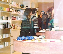 Sophie · 4272 x 2848 Cette photographie montre un **magasin de produits cosmétiques ou artisanaux**. Le **sujet principal** est un groupe de personnes, dont une employée en train de conseiller des clientes.La **composition** est dynamique, avec un **cadrage serré** sur le comptoir et les produits exposés. La **lumière** est naturelle et douce, éclairant bien les couleurs. Les **couleurs dominantes** sont des tons pastel (bleu, rose) et des neutres (blanc, beige).Le **style** est épuré et moderne, évoquant une ambiance **chaleureuse et professionnelle**. L’**ambiance** est conviviale et axée sur le conseil personnalisé.