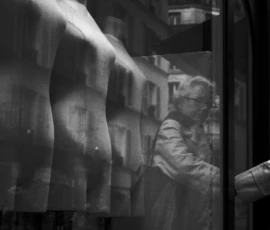 Thomas · 16/05/2026 · 1362 x 2048 Cette photographie en noir et blanc met en scène une personne, vue de dos, à travers une vitre embuée, probablement en train de regarder dehors. La composition joue sur le flou et la transparence partielle, créant une ambiance mystérieuse et intime. Le cadrage serré et légèrement bas accentue cette impression de proximité et d’isolement.La lumière, douce et diffuse, traverse les gouttes d’eau sur la vitre, ajoutant une texture poétique. Les tons gris dominent, renforçant une atmosphère mélancolique et contemplative. Le style rappelle le réalisme photographique, avec une touche onirique due aux effets de la condensation.