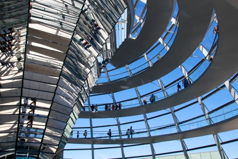 Cédric · 01/05/2026 · 2048 x 1365 Cette photographie montre l'intérieur du dôme en verre du **Reichstag à Berlin**. Le sujet principal est l’architecture spectaculaire avec ses structures circulaires et ses jeux de miroirs.La composition met en valeur la symétrie et la profondeur, renforcée par le cadrage en plongée. La lumière naturelle, filtrée par le verre, crée des reflets bleutés et des contrastes lumineux. Les couleurs dominantes sont les tons froids (bleu, gris) et quelques touches de blanc.Le style est moderne et épuré, évoquant une ambiance à la fois futuriste et transparente, symbolisant l’ouverture et la démocratie.