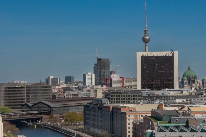 Cédric · 01/05/2026 · 2048 x 1365 Cette photographie montre une vue urbaine de Berlin. Le **sujet principal** est la **Tour de télévision (Fernsehturm)**, emblématique, au centre. La **composition** met en valeur un horizon varié avec des bâtiments modernes et historiques.Le **cadrage** est large, incluant un plan général de la ville et une partie du fleuve. La **lumière** est naturelle et claire, typique d’un jour ensoleillé. Les **couleurs dominantes** sont les tons gris des bâtiments, contrastés par le bleu du ciel et les touches de vert des arbres.Le style est **réaliste et documentaire**, capturant une ambiance **urbaine dynamique et moderne**.