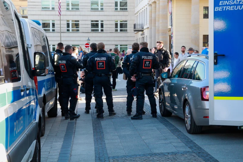 Cédric · 01/05/2026 · 2048 x 1365 Cette photographie montre un groupe d’agents de police en uniforme discutant près de véhicules de secours et de police. Le sujet principal est ces agents, alignés en cercle.La composition est dynamique, avec un cadrage serré sur les uniformes et les véhicules. La lumière est naturelle, légèrement tamisée, créant des ombres douces. Les couleurs dominantes sont les bleus (uniformes, véhicules) et les gris (bâtiments, sol).Le style est documentaire, réaliste, reflétant une scène urbaine. L’ambiance est professionnelle et sérieuse, évoquant une intervention ou une coordination policière.