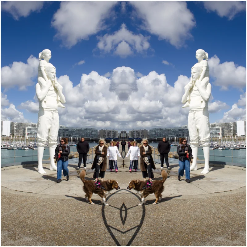 Fabienne · 4000 x 4000 Cette photographie met en scène un groupe de personnes et leurs chiens posant devant deux grandes statues blanches en forme de silhouettes humaines. Le sujet principal est le groupe, encadré par les statues, créant une composition symétrique et harmonieuse.Le cadrage est serré sur le groupe, avec un arrière-plan de ciel bleu et de ville. La lumière est naturelle et éclatante, soulignant les contours et les détails. Les couleurs dominantes sont les tons blancs des statues, les bleus du ciel et les teintes naturelles des vêtements et des animaux.Le style est photographique classique, avec une ambiance joyeuse et festive.