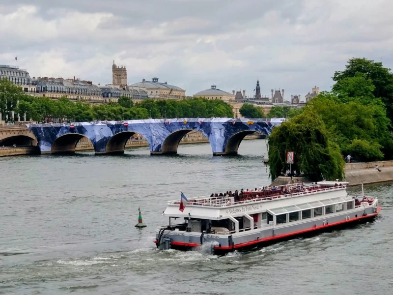 Fabienne · 20/05/2026 · 2186 x 1639 Cette photographie montre un **bateau-mouche** sur la Seine, sujet principal. La **composition** associe le navire en premier plan et le **pont des Arts** en arrière-plan, encadré par des bâtiments historiques.Le **cadrage** est large, capturant une vue panoramique. La **lumière** est naturelle, légèrement voilée par des nuages, créant une ambiance douce. Les **couleurs dominantes** sont les bleus du ciel et de l’eau, les verts des arbres, et les tons gris-beige des bâtiments.Le style est **réaliste et documentaire**, évoquant une **ambiance paisible et touristique** typique de Paris.