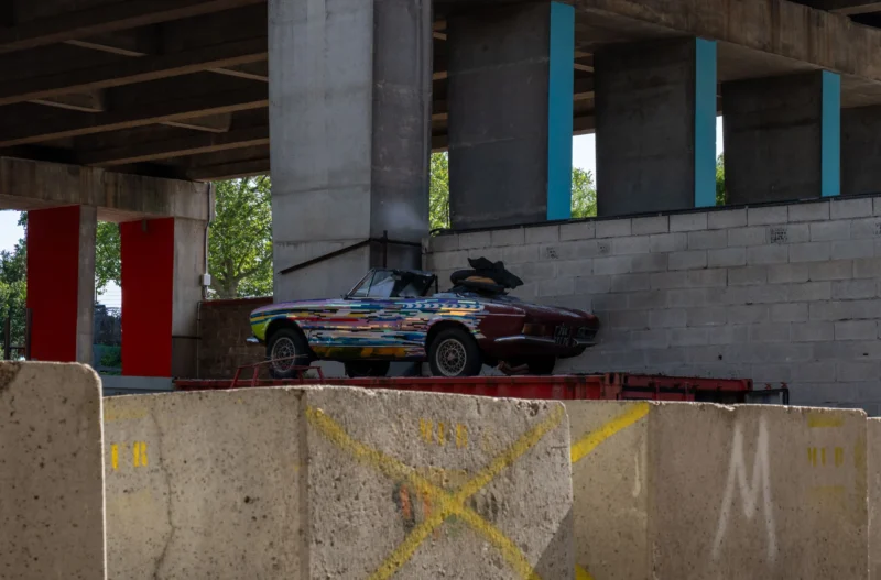 Marc L. · 14/06/2026 · 3869 x 2547 Cette photographie capture une voiture de rallye en action sous un pont en construction. Le **sujet principal** est la voiture, en mouvement sur une rampe en béton.La **composition** est dynamique, avec un **cadrage serré** mettant en valeur la trajectoire et la vitesse. Les **couleurs dominantes** sont les tons gris du béton, les bleus et verts de l’arrière-plan, et les couleurs vives de la voiture (bleu, rouge, blanc).La **lumière** semble naturelle, avec des contrastes marqués. L’**ambiance** est industrielle et sportive, évoquant l’adrénaline et l’audace. Le style est réaliste et documentaire.
