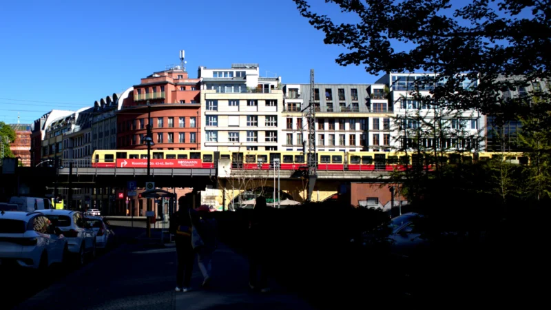 Fabienne · 01/05/2026 · 4082 x 2297 Cette photographie montre une ville avec un tramway rouge comme sujet principal. La composition met en avant un cadrage urbain, avec des bâtiments variés en arrière-plan, dont un style architectural classique et moderne.La lumière est naturelle et vive, suggérant un jour ensoleillé. Les couleurs dominantes sont les tons pastel des bâtiments, contrastant avec le rouge vif du tramway et le vert des arbres. L’ambiance est dynamique et moderne, reflétant une ville animée et bien structurée.