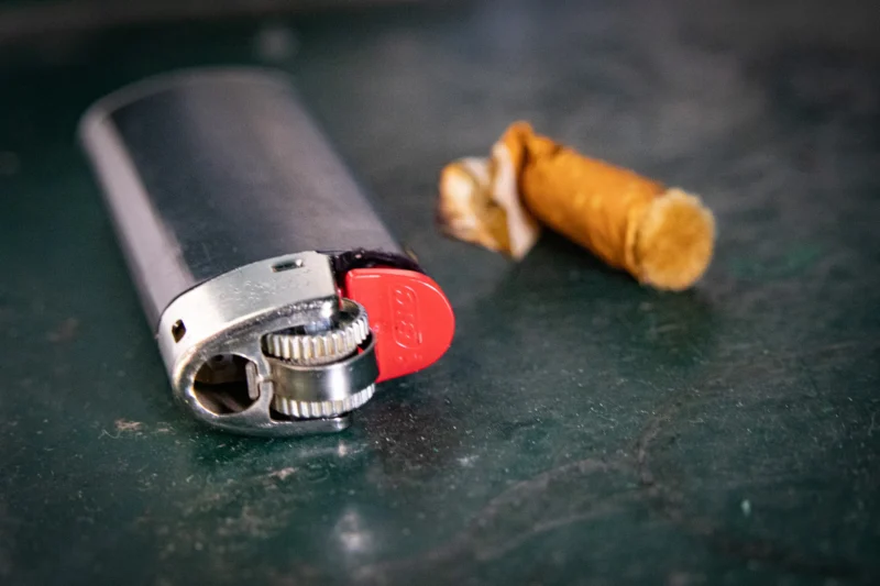 Muriel · 20/06/2026 · 2048 x 1365 Cette photographie met en scène un briquet argenté ouvert, avec une flamme rouge visible, et un petit embout en liège jaune à côté. La composition est simple et épurée, centrée sur ces deux éléments.Le cadrage est serré, mettant en valeur les détails. La lumière semble naturelle et douce, éclairant les objets de manière uniforme. Les couleurs dominantes sont le gris métallique du briquet, le rouge vif de la flamme et le jaune du liège, créant un contraste saisissant.L’ambiance est à la fois minimaliste et intrigante, évoquant une touche d’originalité et de simplicité stylistique.