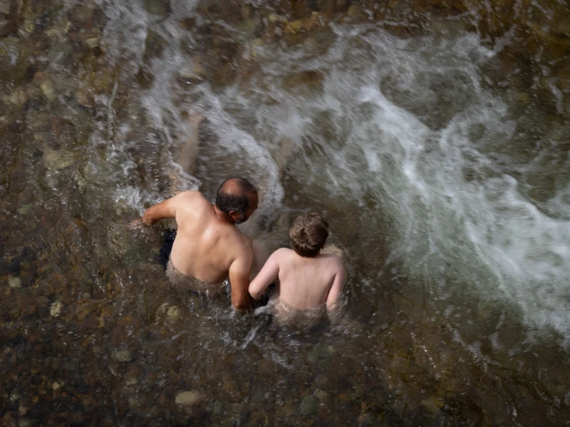 Muriel · 28/06/2026 · 2048 x 1463 Cette photographie montre deux enfants nus, allongés dans une rivière agitée. Le sujet principal est leur complicité et leur immersion dans l’eau.La composition est dynamique, avec un cadrage serré qui isole les enfants. La lumière, naturelle et tamisée, crée des reflets sur l’eau et des contrastes doux. Les couleurs dominantes sont les teintes bleutées et grises de l’eau, avec des nuances chaudes sur les peaux des enfants.Le style est documentaire et spontané, évoquant une ambiance naturelle et intime, presque poétique. L’image dégage une sensation de liberté et de connexion avec la nature.