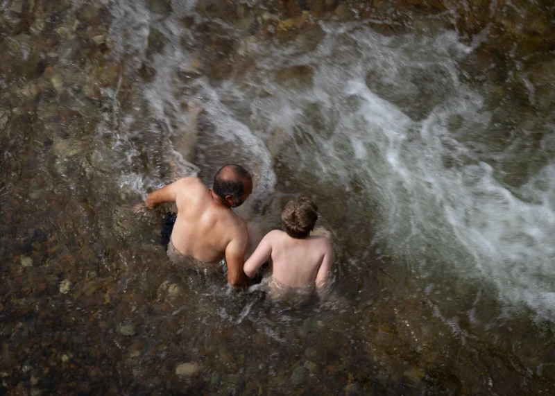 Muriel · 28/06/2026 · 2048 x 1463 Cette photographie montre deux enfants nus, allongés dans une rivière agitée. Le sujet principal est leur complicité et leur immersion dans l’eau.La composition est dynamique, avec un cadrage serré qui isole les enfants. La lumière, naturelle et tamisée, crée des reflets sur l’eau et des contrastes doux. Les couleurs dominantes sont les teintes bleutées et grises de l’eau, avec des nuances chaudes sur les peaux des enfants.Le style est documentaire et spontané, évoquant une ambiance naturelle et intime, presque poétique. L’image dégage une sensation de liberté et de connexion avec la nature.