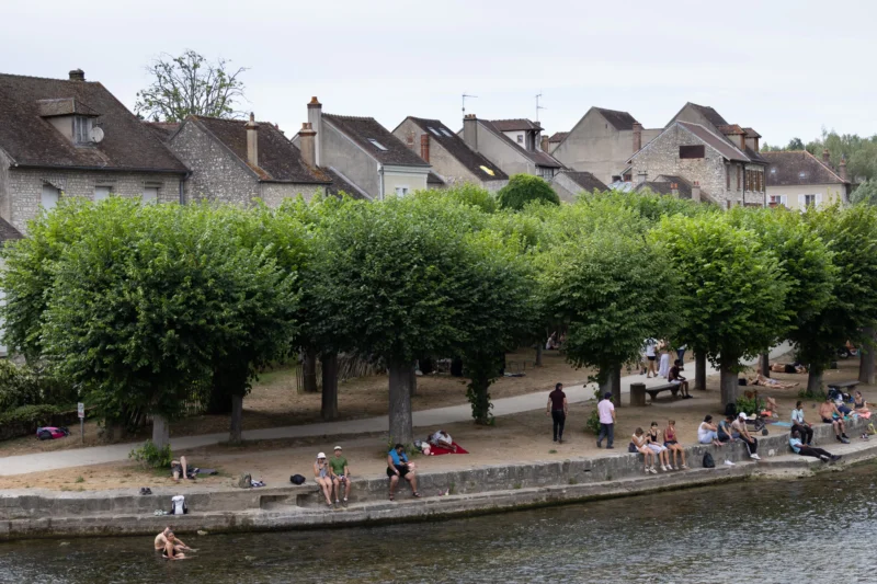 Muriel · 28/06/2026 · 2048 x 1365 Cette photographie montre une scène urbaine paisible le long d'un canal. Le **sujet principal** est le **quai animé**, bordé de **grands arbres** et de **maisons traditionnelles** en arrière-plan.La **composition** est équilibrée, avec une perspective légèrement en hauteur. Le **cadrage** inclut une partie du canal et des passants, créant une ambiance vivante. La **lumière** semble naturelle, sans ombre marquée, suggérant un jour nuageux.Les **couleurs dominantes** sont les verts des arbres, les tons beiges des bâtiments et les reflets bleutés du canal. Le style est **documentaire et réaliste**, évoquant une **ambiance calme et quotidienne** dans un cadre urbain harmonieux.