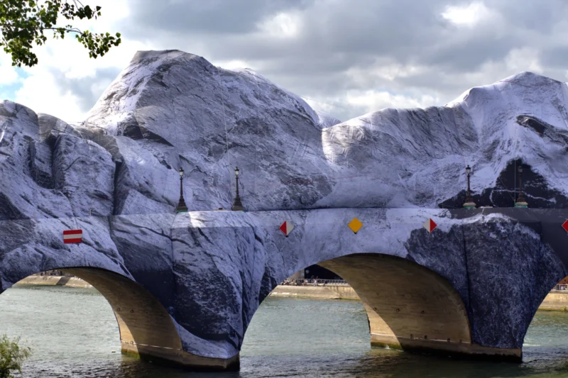 Fabienne · 12/06/2026 · 4844 x 3230 Cette photographie montre un pont recouvert de neige, formant des structures sculpturales impressionnantes. Le sujet principal est ce pont enjambant un plan d’eau calme.La composition met en valeur les arches et les piliers enneigés, avec un cadrage serré qui accentue leur forme organique. La lumière, douce et diffuse, crée des contrastes entre les zones ombragées et éclairées. Les couleurs dominantes sont les blancs de la neige, les gris des pierres et les bleus froids de l’eau et du ciel.Le style est réaliste et photographique, évoquant une ambiance mystérieuse et presque onirique, typique d’un paysage hivernal.