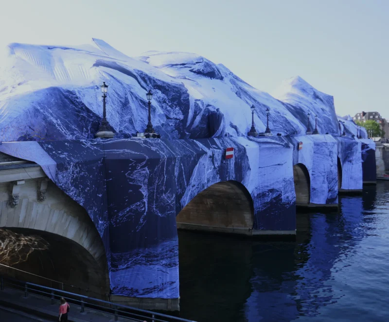 Bao · 4406 x 3648 Cette photographie montre une série de bateaux recouverts de bâches bleues, alignés sur l’eau. Le sujet principal est ces embarcations, probablement en attente ou en stockage.La composition est linéaire et symétrique, avec un cadrage serré sur les bateaux. La lumière, naturelle et douce, semble provenir d’un angle latéral, créant des ombres légères. Les couleurs dominantes sont les bleus des bâches et de l’eau, avec des touches de gris et de blanc.Le style est réaliste et documentaire, évoquant une ambiance industrielle et calme, presque mélancolique.