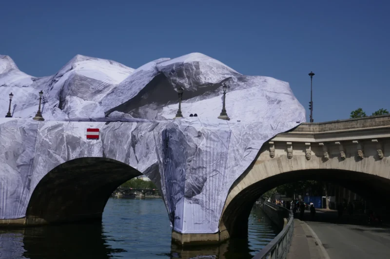 Bao · 5472 x 3648 Cette photographie montre un pont recouvert d’une structure en forme de montagnes de glace artificielles. Le sujet principal est cette installation éphémère, évoquant un paysage polaire.La composition met en valeur les arches du pont et l’eau en contrebas. Le cadrage est serré, centré sur les structures glacées. La lumière est naturelle et éclatante, suggérant un jour ensoleillé. Les couleurs dominantes sont le blanc des "glaces" et le bleu du ciel et de l’eau.Le style est artistique et spectaculaire, créant une ambiance onirique et contrastée entre nature et architecture.