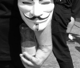 Franck T. · 30/05/2026 · 897 x 1400 Cette photographie met en scène un masque Guy Fawkes, symbole de l'anonymat et de la rébellion. Le sujet principal est un individu vêtu d’un costume noir, dont seul le masque est visible en gros plan. La composition est serrée, centrée sur le visage masqué, avec un cadrage rapproché qui accentue les détails du masque et des mains.En noir et blanc, l'image joue sur les contrastes lumineux, renforçant l'atmosphère mystérieuse et dramatique. Le style est documentaire et percutant, évoquant une ambiance de protestation ou de contestation sociale.