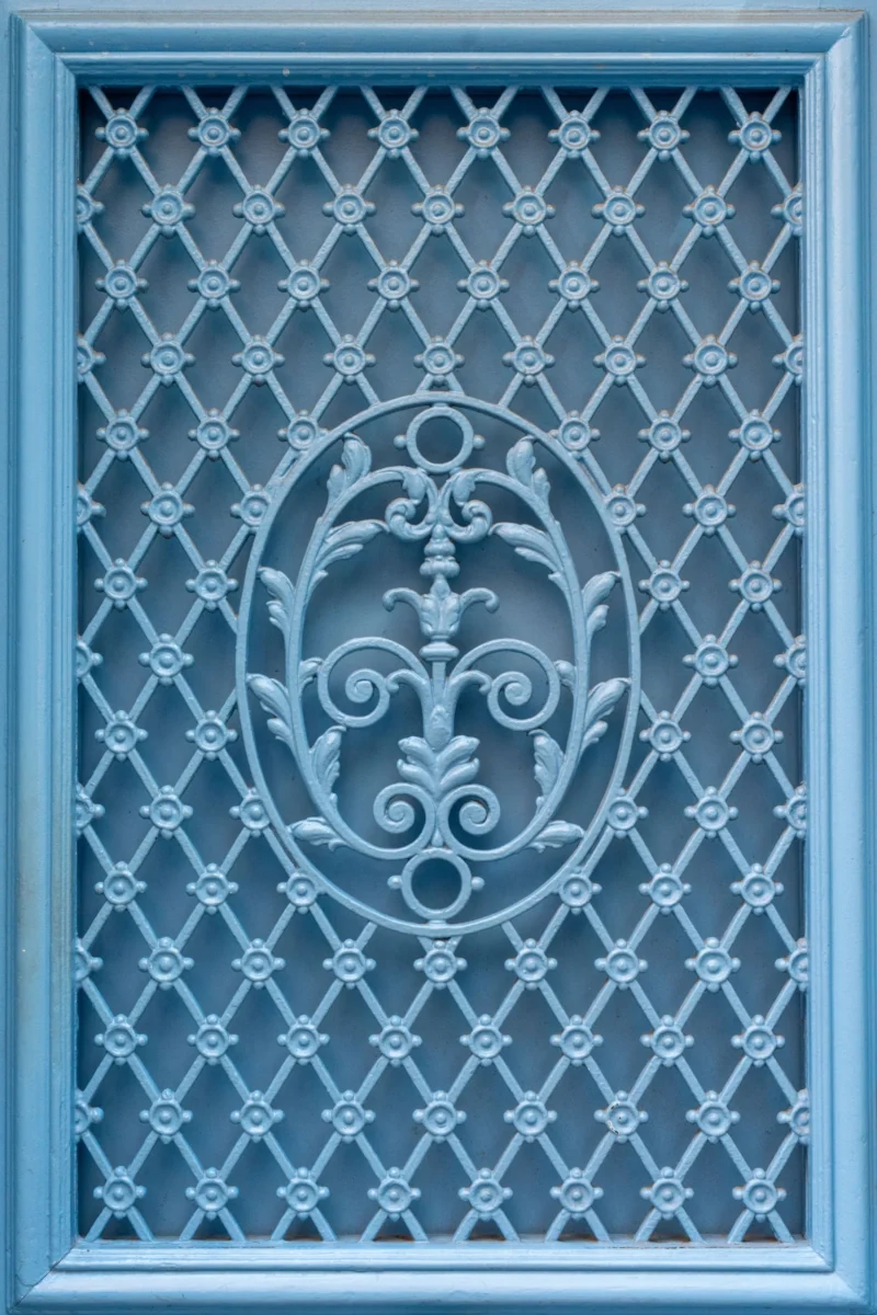 Marc L. · 20/06/2026 · 4321 x 6481 Cette photographie montre une fenêtre à carreaux décorative. Le sujet principal est un motif central en forme d’ovale, orné de motifs floraux et de volutes stylisées, typiques d’un style baroque ou Art nouveau.La composition est symétrique, avec un cadrage serré mettant en valeur les détails. La lumière semble douce et uniforme, éclairant les motifs sans créer d’ombres marquées. Les couleurs dominantes sont des bleus grisâtres et des teintes bleutées, renforçant une ambiance sobre et élégante. L’ensemble dégage une impression de raffinement et de nostalgie.