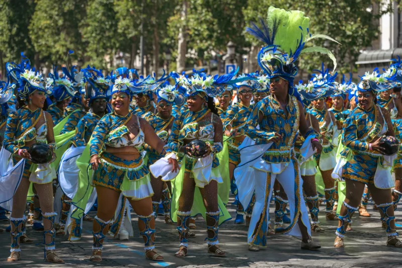 Daniel · 05/07/2026 · 5275 x 3517 Cette photographie capture une défilé festif avec un groupe de danseurs comme sujet principal. La composition montre une formation serrée en mouvement, avec des danseurs vêtus de costumes traditionnels colorés.Le cadrage est serré sur les participants, mettant en valeur leurs tenues et leurs expressions. La lumière est naturelle et généreuse, éclairant clairement la scène. Les couleurs dominantes sont le bleu turquoise, le vert et le blanc, créant une ambiance vibrante et joyeuse. Le style évoque une célébration culturelle, probablement une fête traditionnelle ou un carnaval. L’ambiance est dynamique et festive.