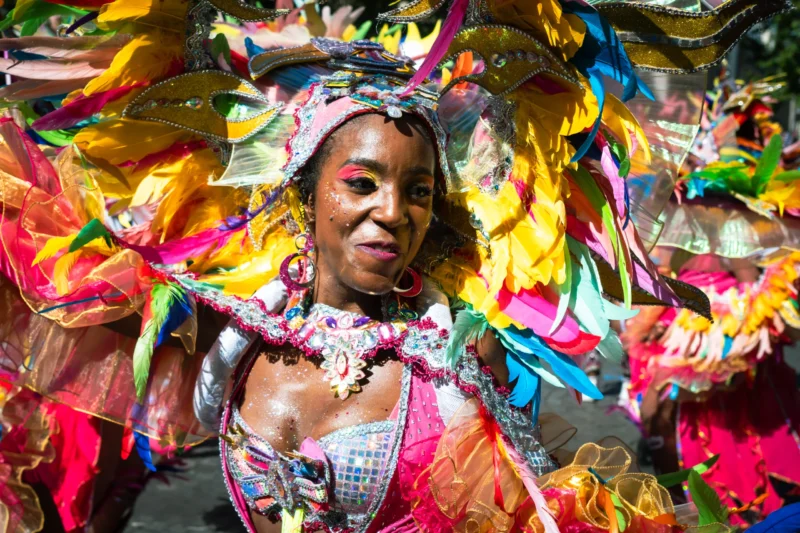 Daniel · 05/07/2026 · 5728 x 3819 Cette photographie met en scène une femme comme sujet principal, vêtue d’un costume festif et coloré. La composition est centrée sur elle, avec un cadrage serré qui isole son visage et ses épaules.La lumière est naturelle et met en valeur ses traits, créant un contraste doux. Les couleurs dominantes sont vives : roses, jaunes, verts et bleus éclatants, typiques d’une tenue de carnaval.Le style est dynamique et joyeux, évoquant une ambiance festive et exubérante. L’ensemble dégage une énergie positive et célébrative.