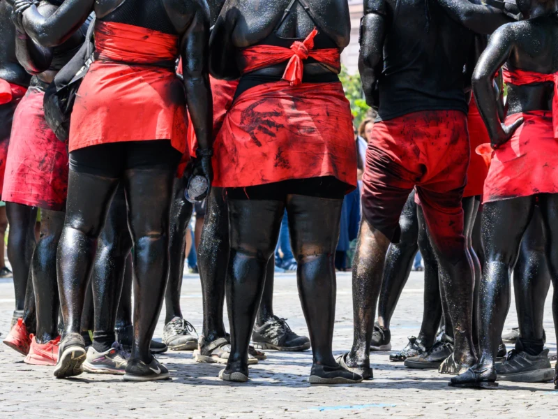 Daniel · 05/07/2026 · 4179 x 2786 Cette photographie montre un groupe de personnes vêtues de tenues traditionnelles. Le sujet principal est leurs jambes et leurs bas de costumes : pantalons noirs et ceintures/écharpes rouges.La composition est serrée, avec un cadrage en plan rapproché, mettant en avant les détails des vêtements. La lumière semble naturelle, bien répartie, sans ombres marquées. Les couleurs dominantes sont le noir et le rouge, créant un contraste saisissant.Le style est documentaire, captant une scène culturelle ou rituelle. L’ambiance est solennelle et dynamique, évoquant une célébration ou une cérémonie collective.