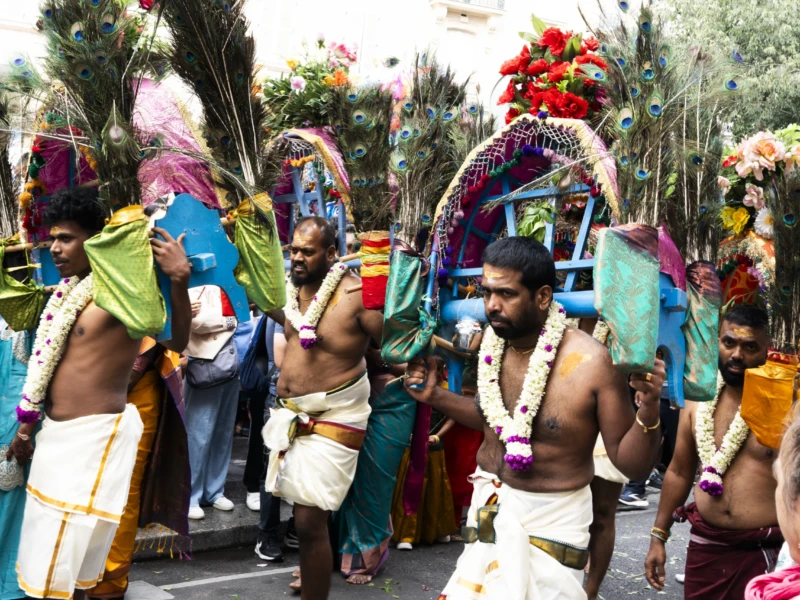 Alice · 30/08/2026 · 3840 x 2560 Cette photographie capture une procession culturelle traditionnelle. Le sujet principal est un groupe de danseurs vêtus de costumes colorés, dont l’un porte une coiffure ornée et des accessoires floraux.La composition montre une scène dynamique, avec les danseurs alignés et en mouvement. Le cadrage est serré, mettant en valeur les détails des costumes et des expressions. La lumière naturelle éclaire la scène, créant des contrastes doux. Les couleurs dominantes sont vives : verts, bleus, jaunes et rouges, typiques des célébrations festives.L’ambiance est joyeuse et rituelle, évoquant une fête ou une cérémonie traditionnelle.