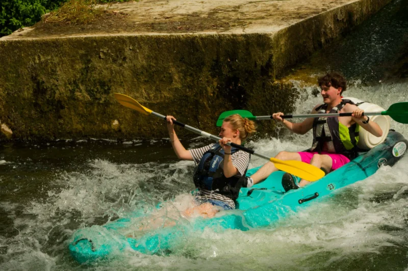 Monique · 01/08/2026 · 5358 x 3563 Deux personnes en kayak naviguent sur une rivière rapide avec des mouvements dynamiques et des éclaboussures autour d'eux