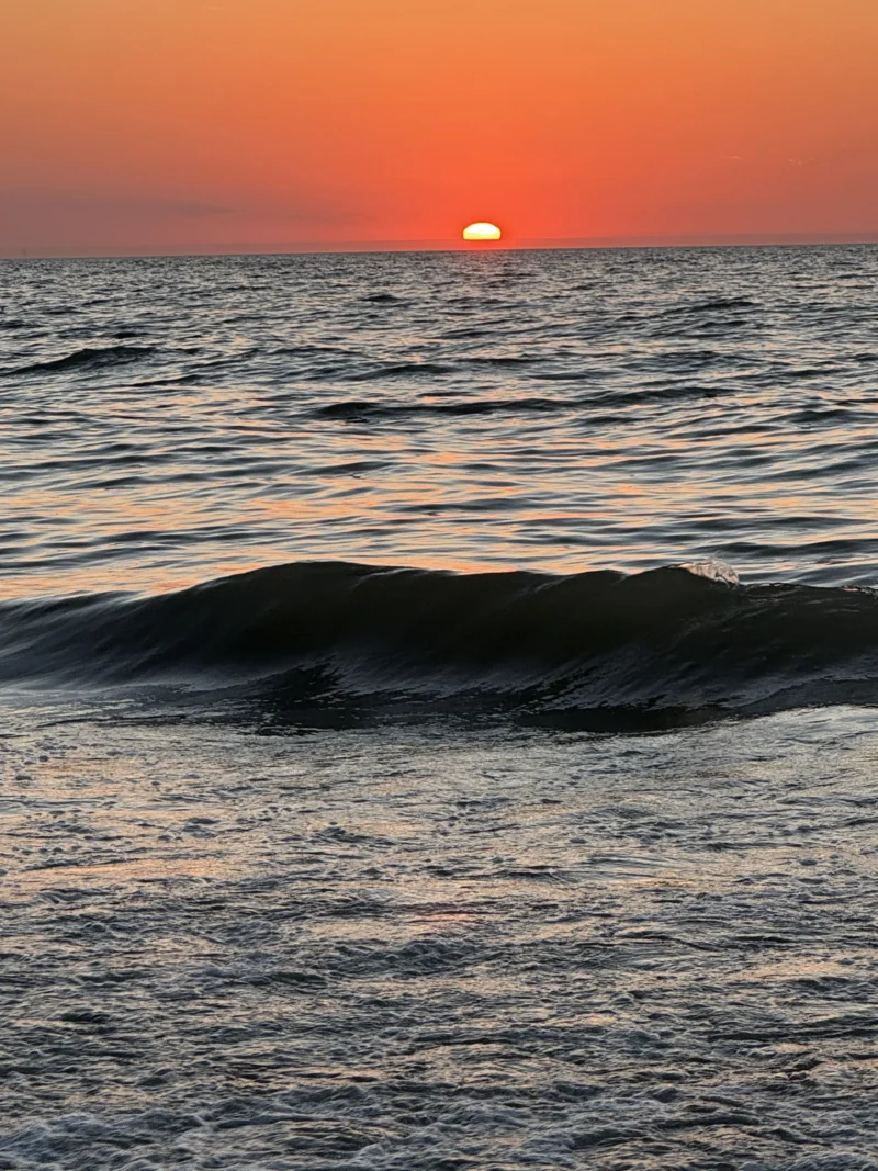 Heike · 12/08/2026 · 4032 x 3024 Couchant sur l'océan avec une vague sombre en premier plan et un soleil rougeoyant à l'horizon, ambiance sereine et lumineuse