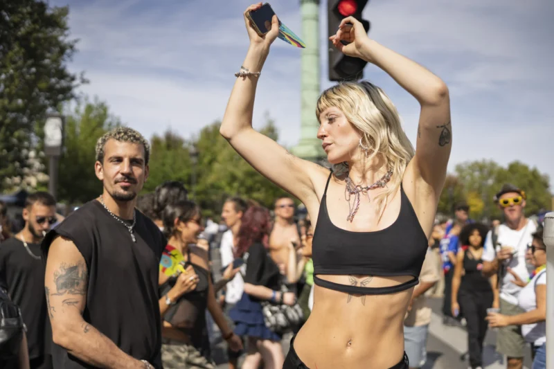 Thierry · 19/09/2026 · 3840 x 2560 Deux personnes en plein air, l'une prenant une photo avec un smartphone tandis que l'autre pose avec les bras levés