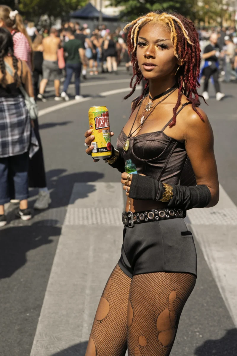 Thierry · 19/09/2026 · 2560 x 3840 Personne en costume cosplay tenant une canette de boisson et un accessoire, lors d’un événement en extérieur avec foule