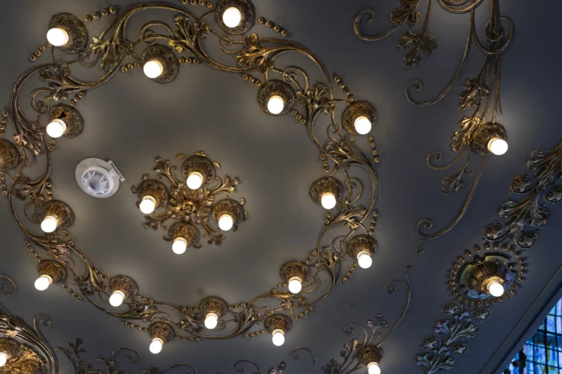 Plafond orné de lustres élégants aux motifs dorés et aux ampoules lumineuses, style baroque, vue plongeante.