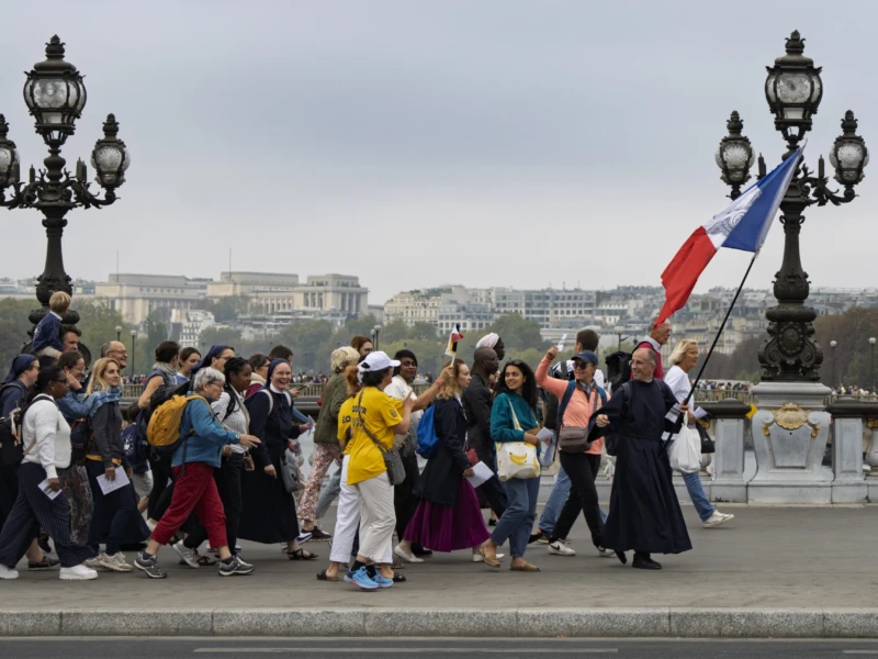 Thierry · 26/09/2026 · 3840 x 2560 Groupe de personnes marchant sur un pont parisien avec une personne brandissant un drapeau français, ambiance touristique
