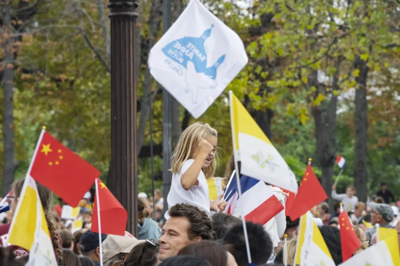 Thierry · 26/09/2026 · 3840 x 2560 Manifestation avec participants brandissant des drapeaux et bannières dans un parc arboré, ambiance festive et engagée