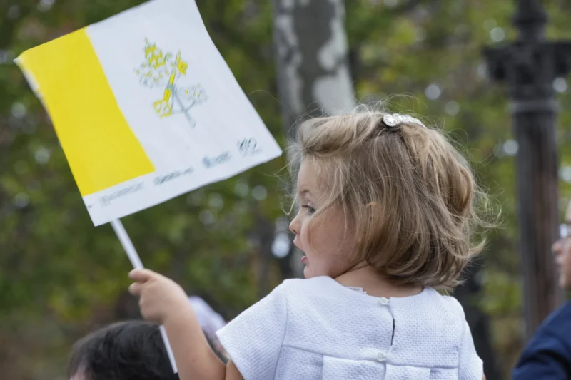 Thierry · 26/09/2026 · 3840 x 2560 Enfant tenant une banderole jaune et blanche avec un dessin floral, participant à une manifestation en extérieur.