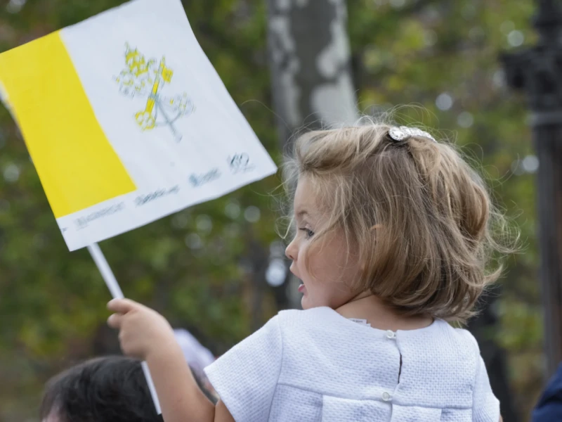 Thierry · 26/09/2026 · 3840 x 2560 Enfant tenant une banderole jaune et blanche avec un dessin floral, participant à une manifestation en extérieur.