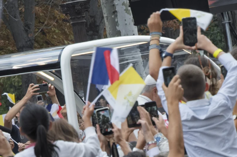Thierry · 26/09/2026 · 3840 x 2560 Groupe de personnes brandissant des drapeaux et prenant des photos avec des smartphones lors d'un rassemblement en extérieur