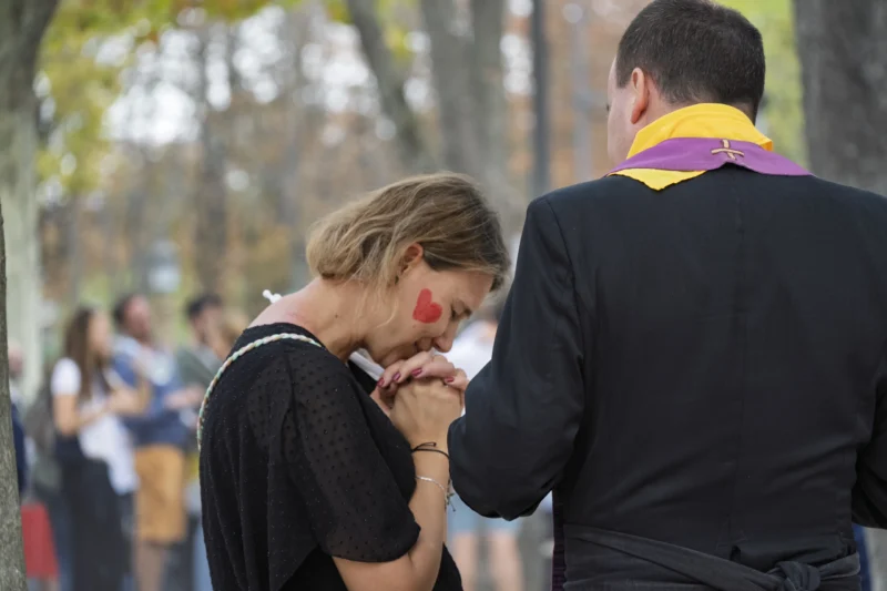 Thierry · 26/09/2026 · 3840 x 2560 Deux personnes en tenue formelle, dont l'une porte une cravate aux couleurs vives, semblent échanger un geste affectueux