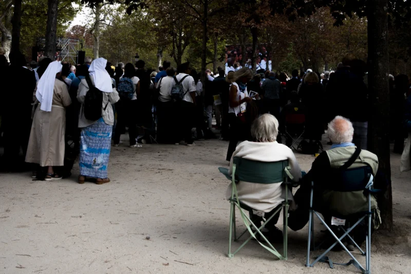 Alice · 26/09/2026 · 3840 x 2560 Groupe de personnes assises et debout dans un parc, certaines écoutant un spectacle en extérieur sous des arbres.